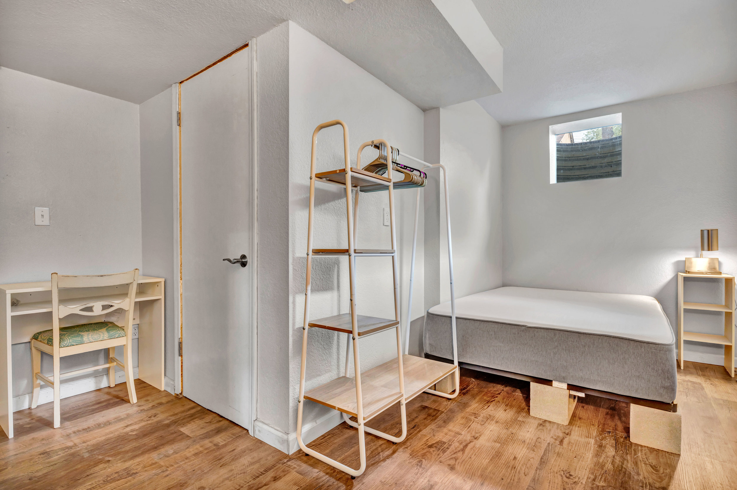 Lower-level bedroom with desk and clothing rack